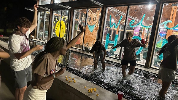 College students playing in a dunk tank filled with water and rubber ducks