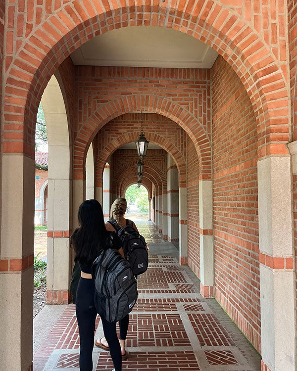 Two people walking through arched hallways