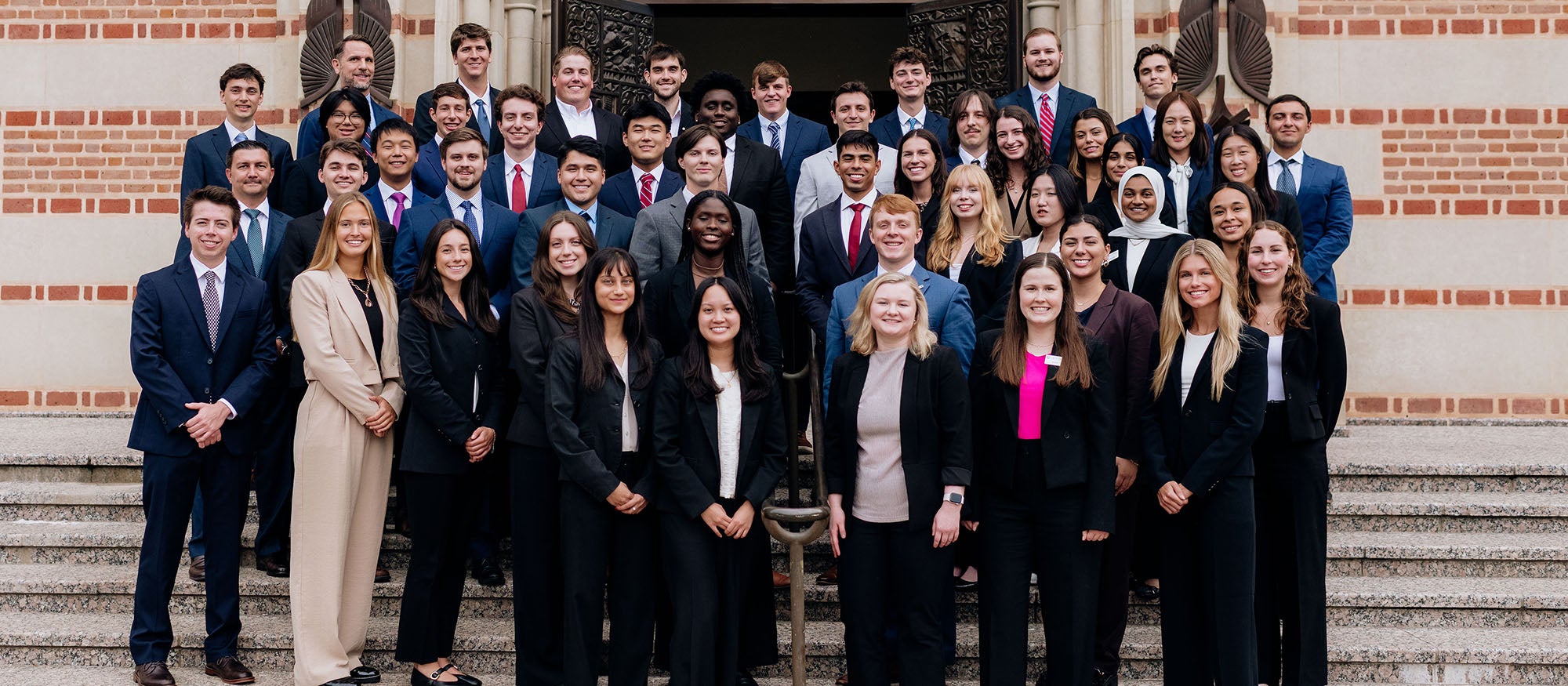 A large group of students in business formal wear standing on stairs