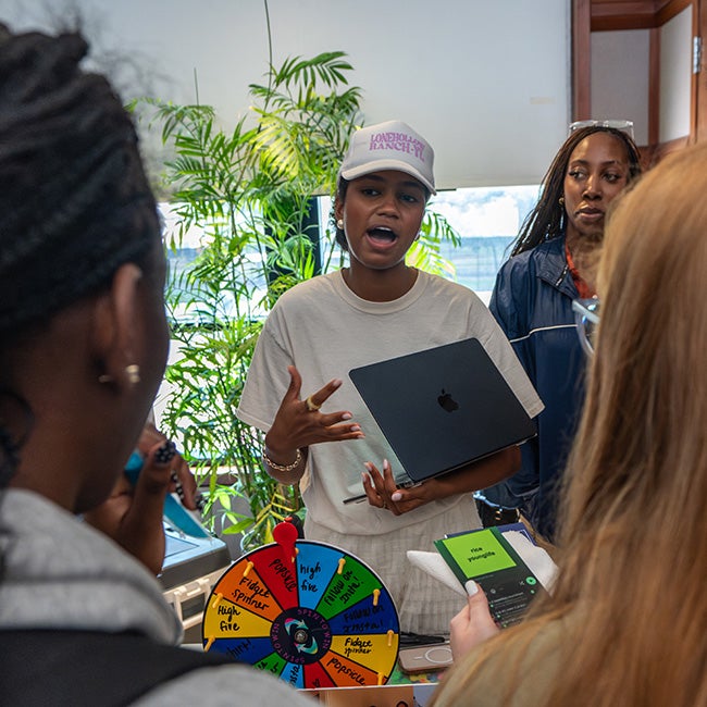 Two heads framing either side of the photo, a lady in the middle with a tablet speaking to both
