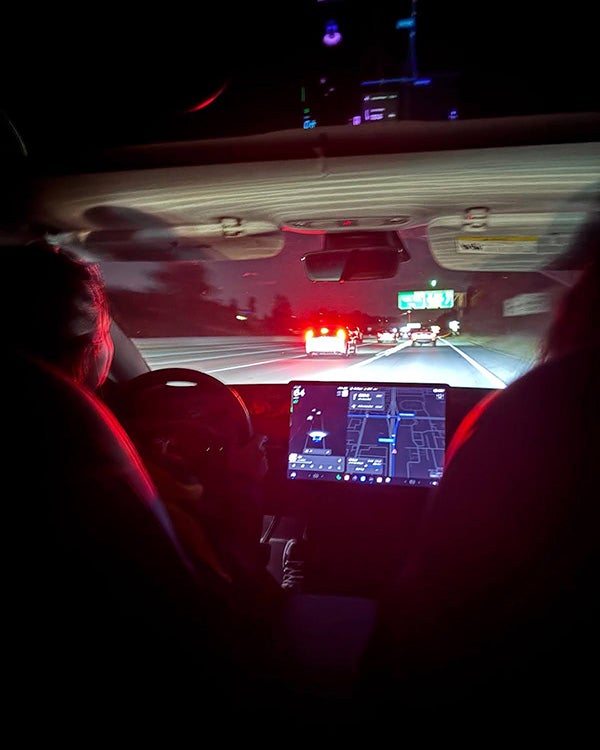 The dashboard of a car at night, as taken from the backseat of the car