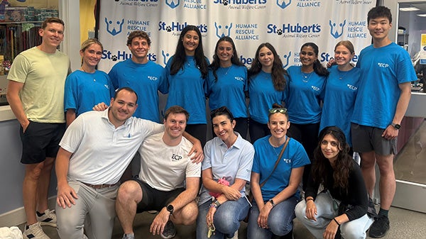 A large group of people posing in front of a branded banner