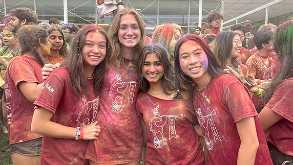 Four female students in matching T-shirts, covered in colors