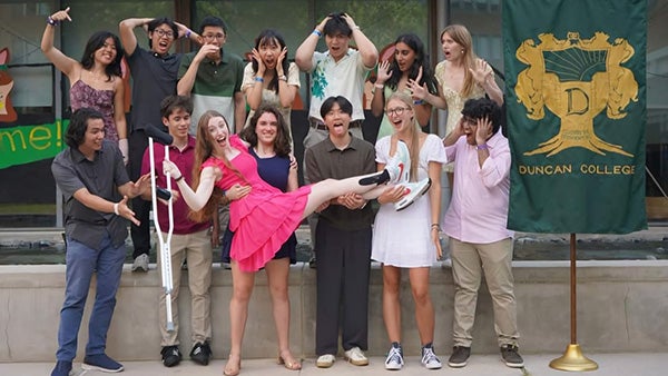 Large group of students hold up one student's leg, which is in a boot