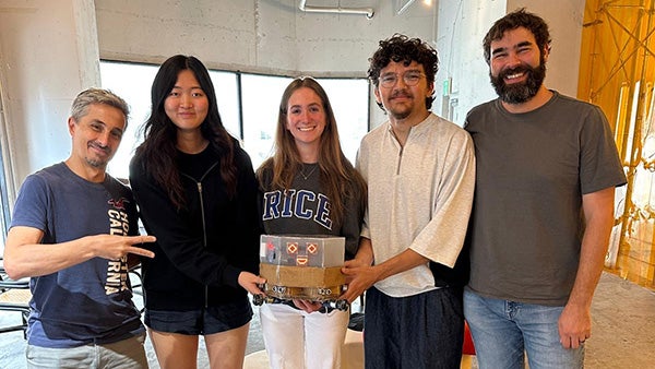 Five people posing for a photo, smiling and holding an engineering innovation