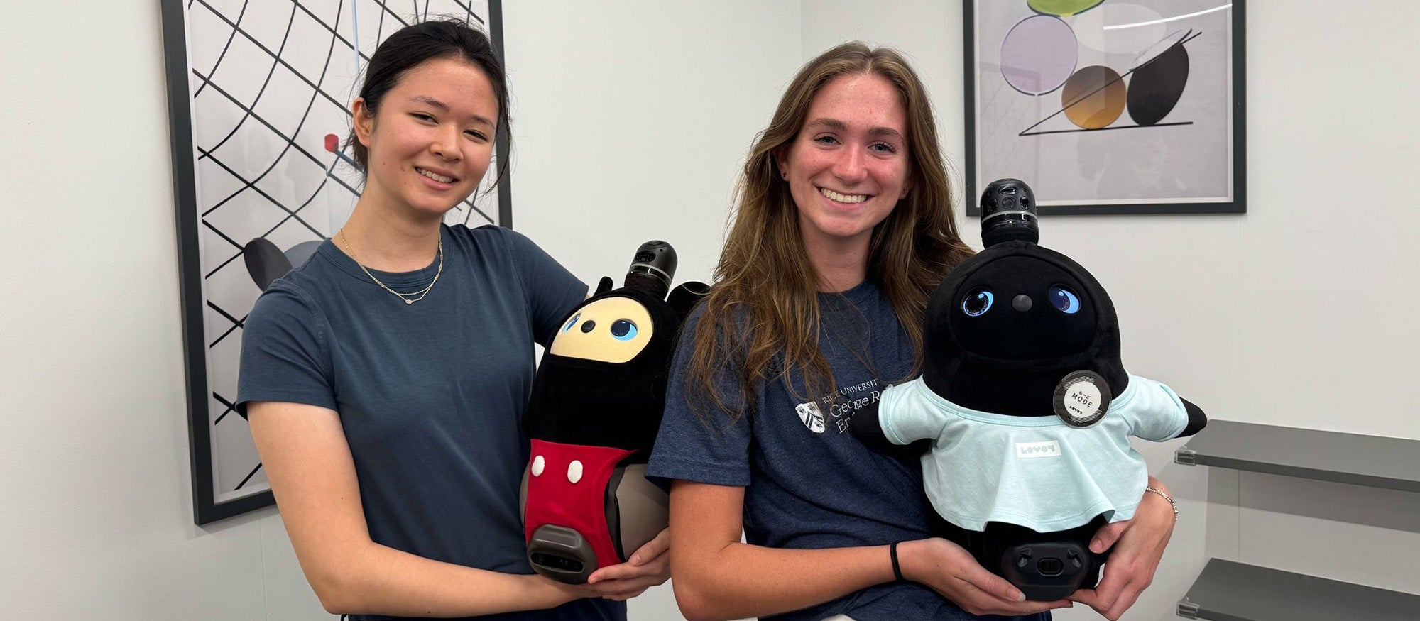 Two girls holding matching robots in their arms