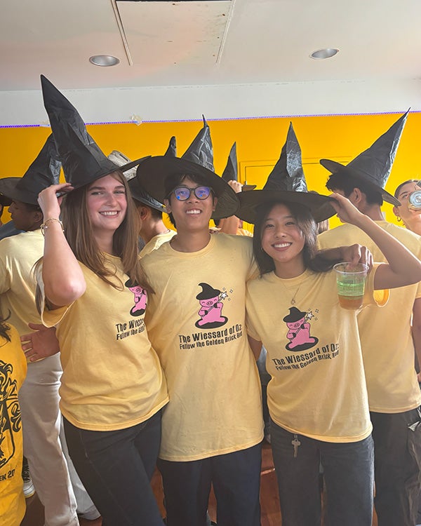 Three people in yellow T-shirts and black wizard hats