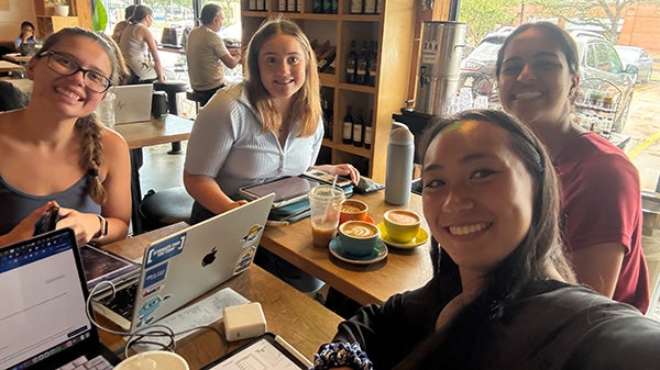 Four girls with laptops take a selfie together