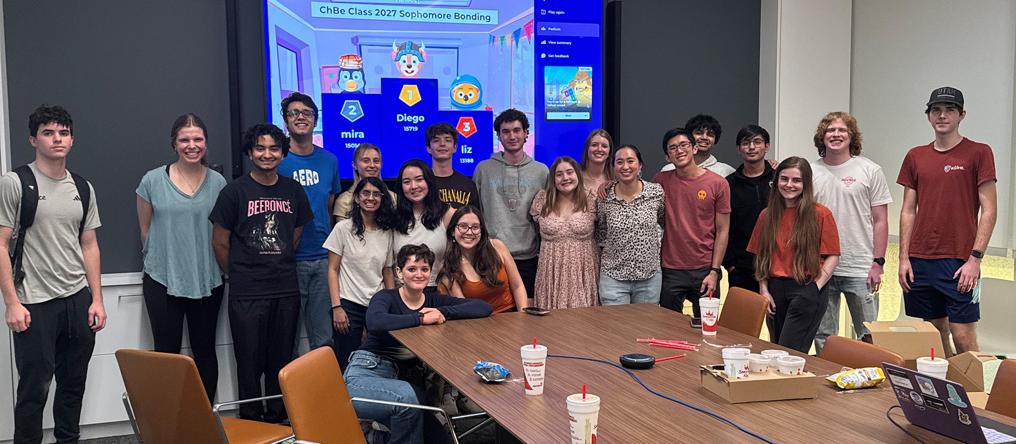 Many students posing in front of a screen