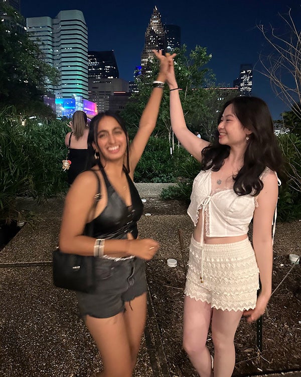 Two girls mid-dance in a cityscape at night
