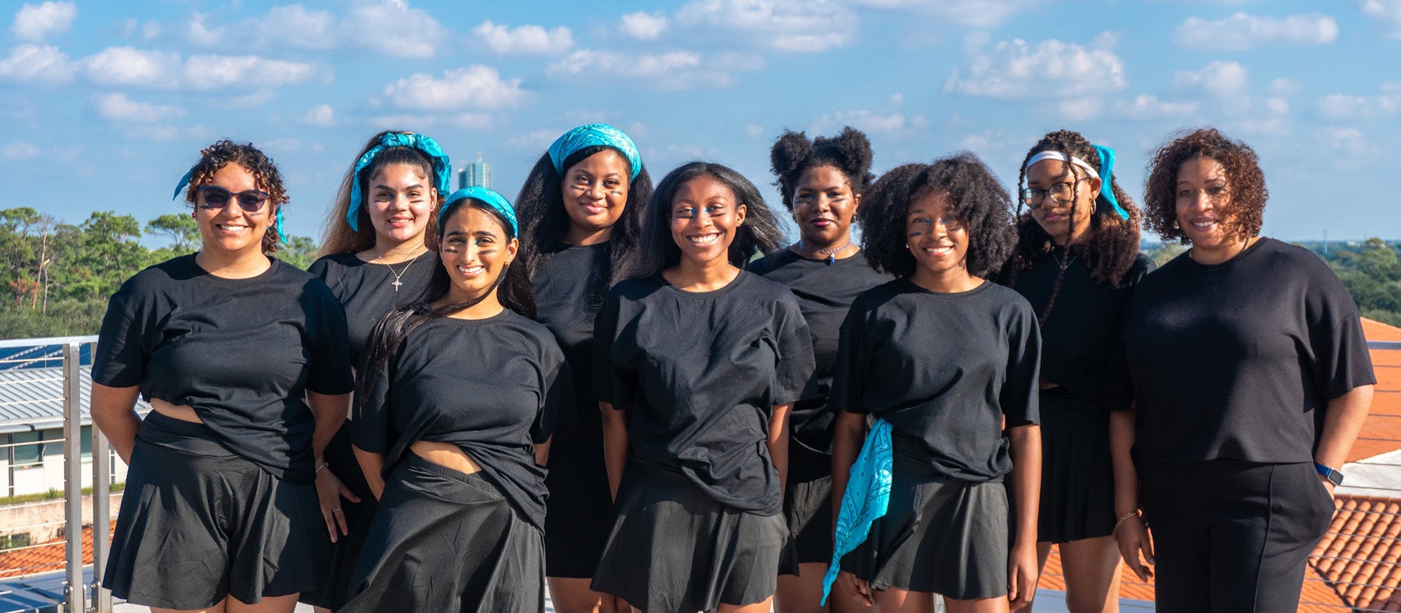 Students in matching black clothing posing for a photo outdoors