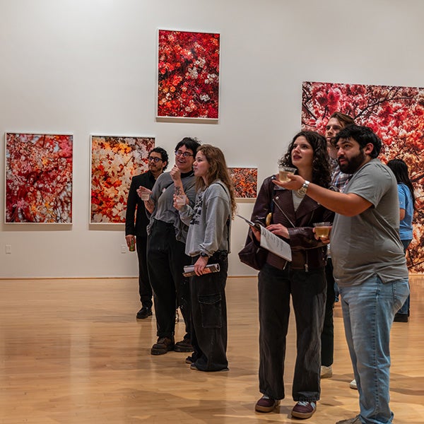 People pointing offscreen; wall with large art behind them