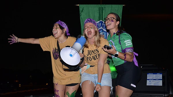 Three people close together, mid-speech, cheering to people off-screen