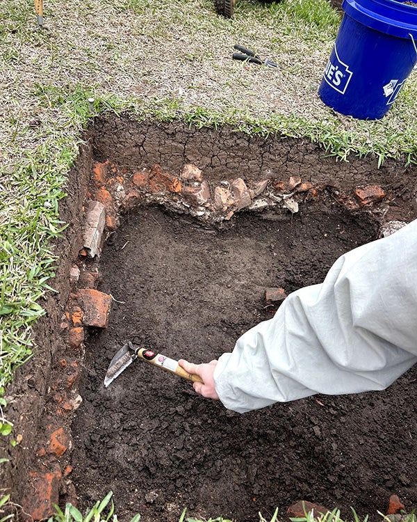 Hand holding tool digging into the earth