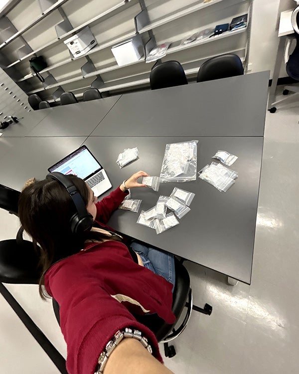 .5 lens selfie of girl sitting at a table, bags in front of her