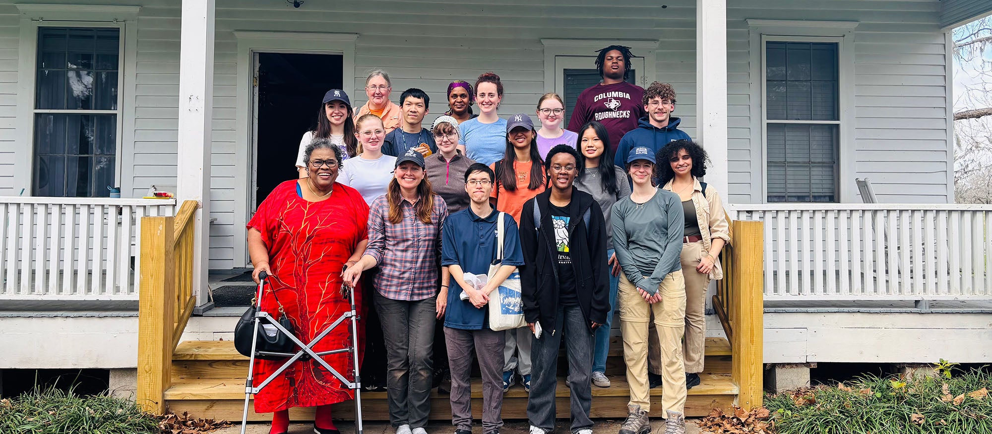 Many people standing in front of a large white house