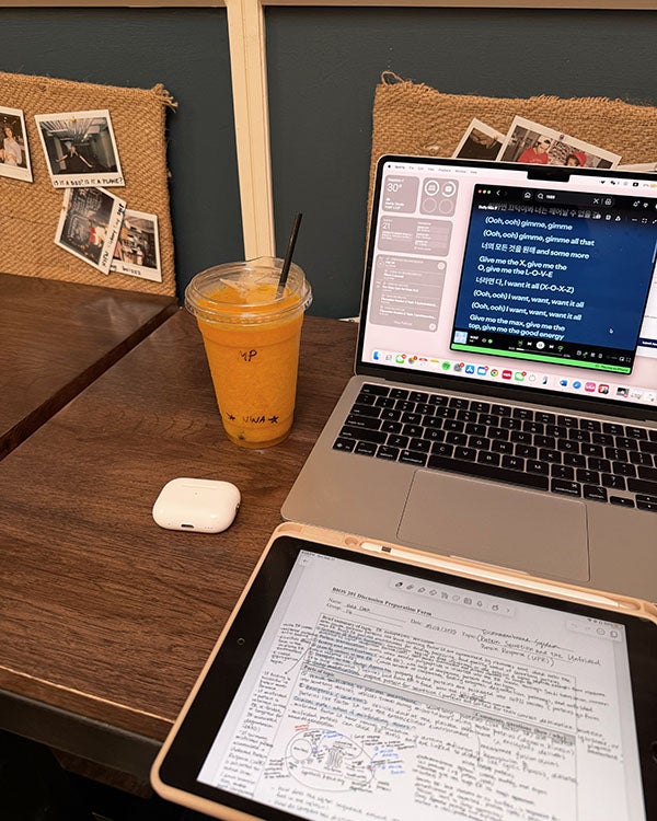 A drink next to a laptop and iPad, all on a table