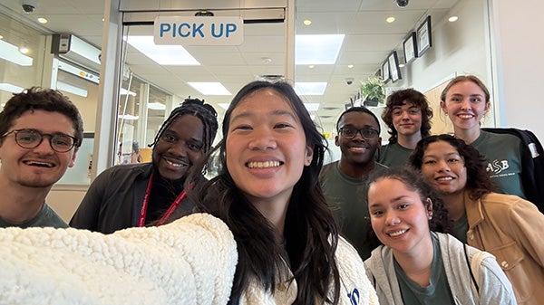 Selfie of several students in front of clear glass window 