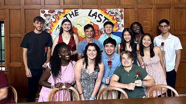 People in formal dress huddled together in front of hand-made banner poster
