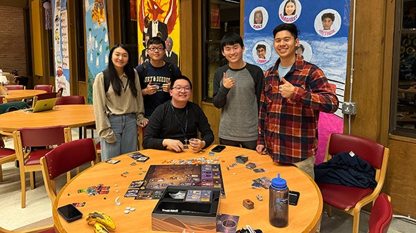 People standing behind a table with a board game on it