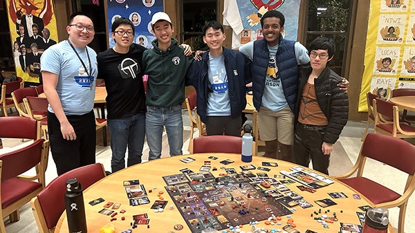 People standing behind a table with a board game on it