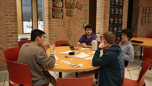 People sitting around a round table with cards on it