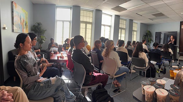 People sitting in chairs facing front of room