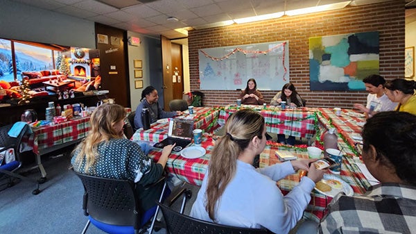 People huddled around a table with colorful tablecloth
