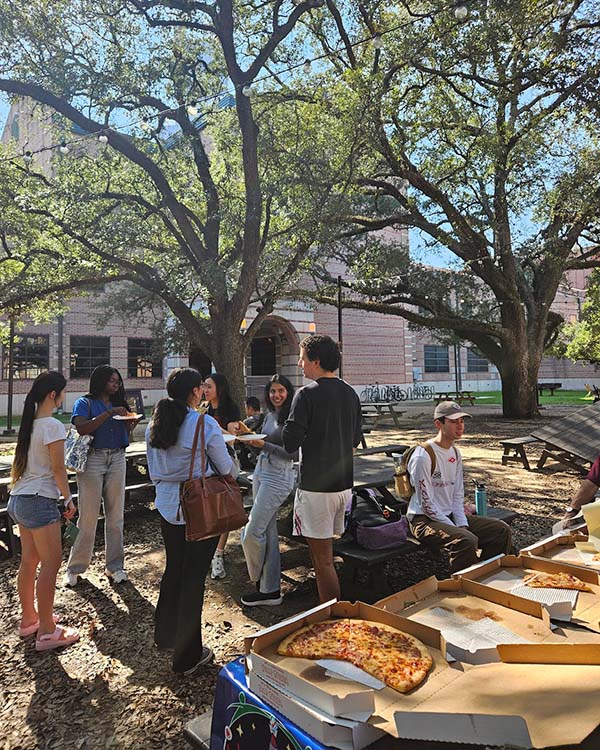 People eating pizza and socializing outdoors