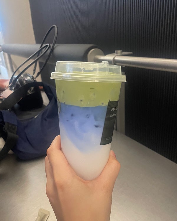 Hand holding blue-and-white matcha drink