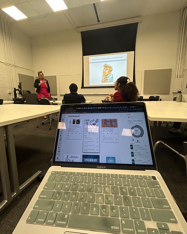 A laptop in a classroom, people in the back