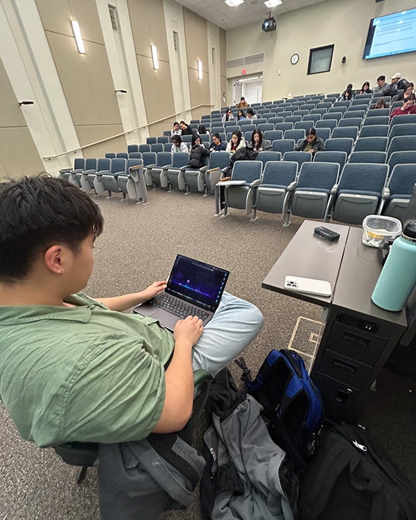 A guy on a laptop in front of a large lecture hall