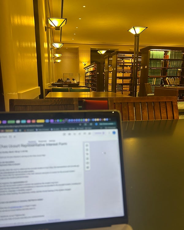 Laptop on a table in warmly lit room with tables and bookshelves