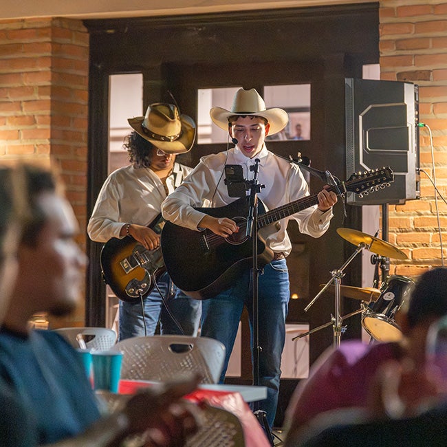 two people playing guitar to a crowd in the foreground