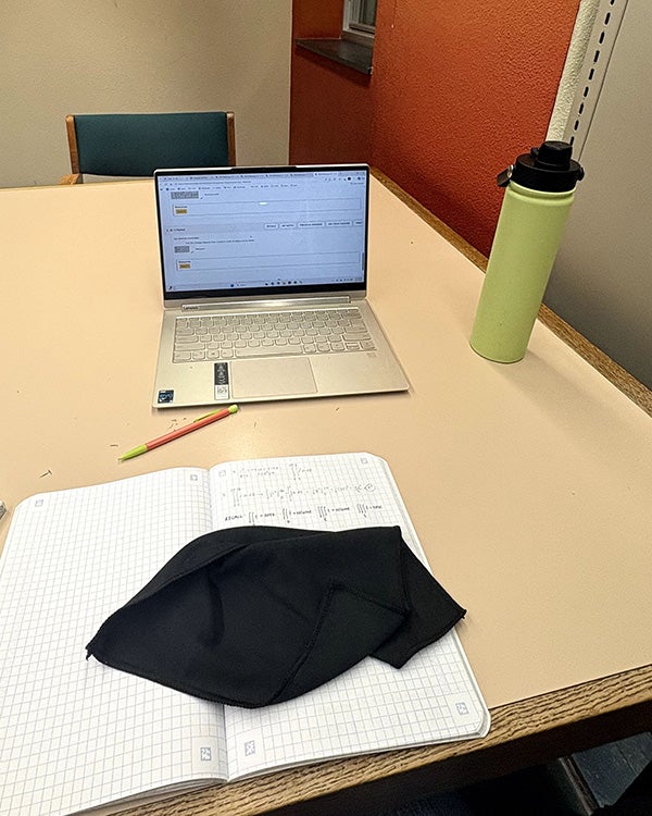 open journal, laptop, and drink tumbler on a table