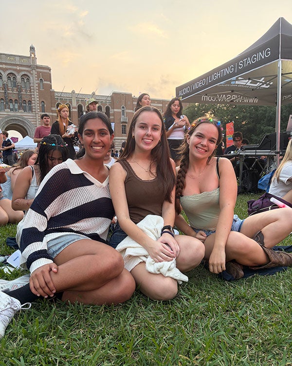 three girls sitting on a lawn together outdoors