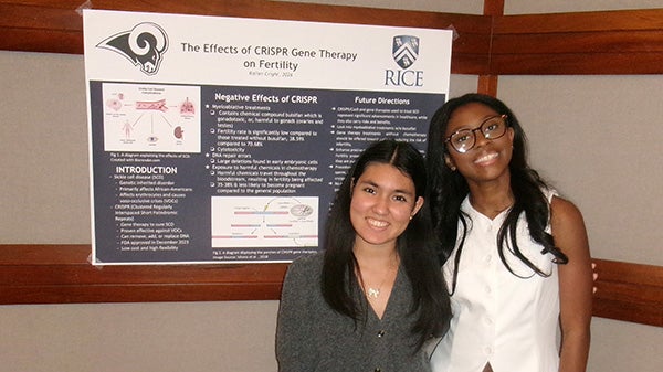 Two girls standing together in front of a poster