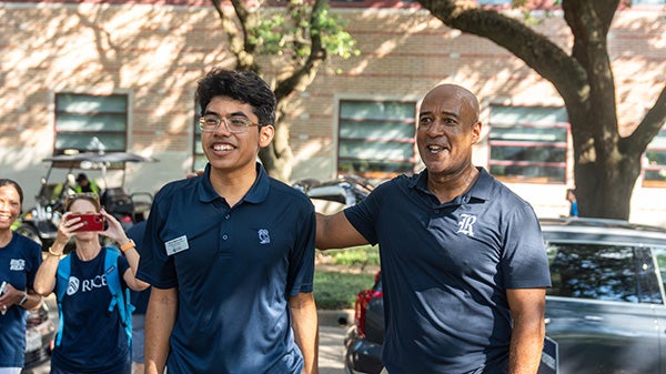 Man with hand on a student's back, both looking off-screen