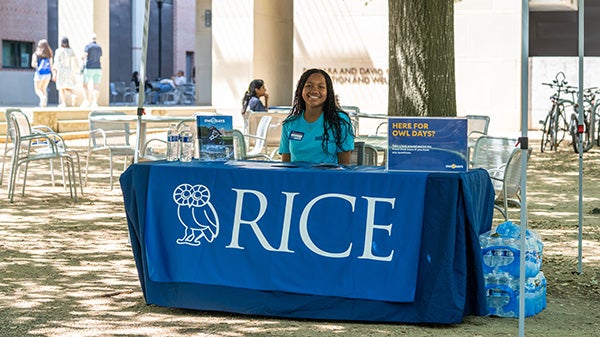 A woman sitting at a table with a Rice University branded table cover