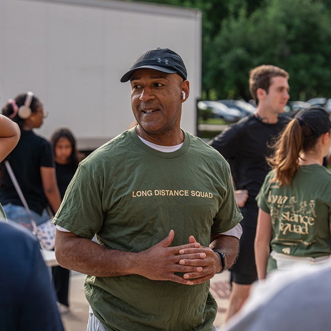 Man in cap and green shirt standing among people in similar clothing