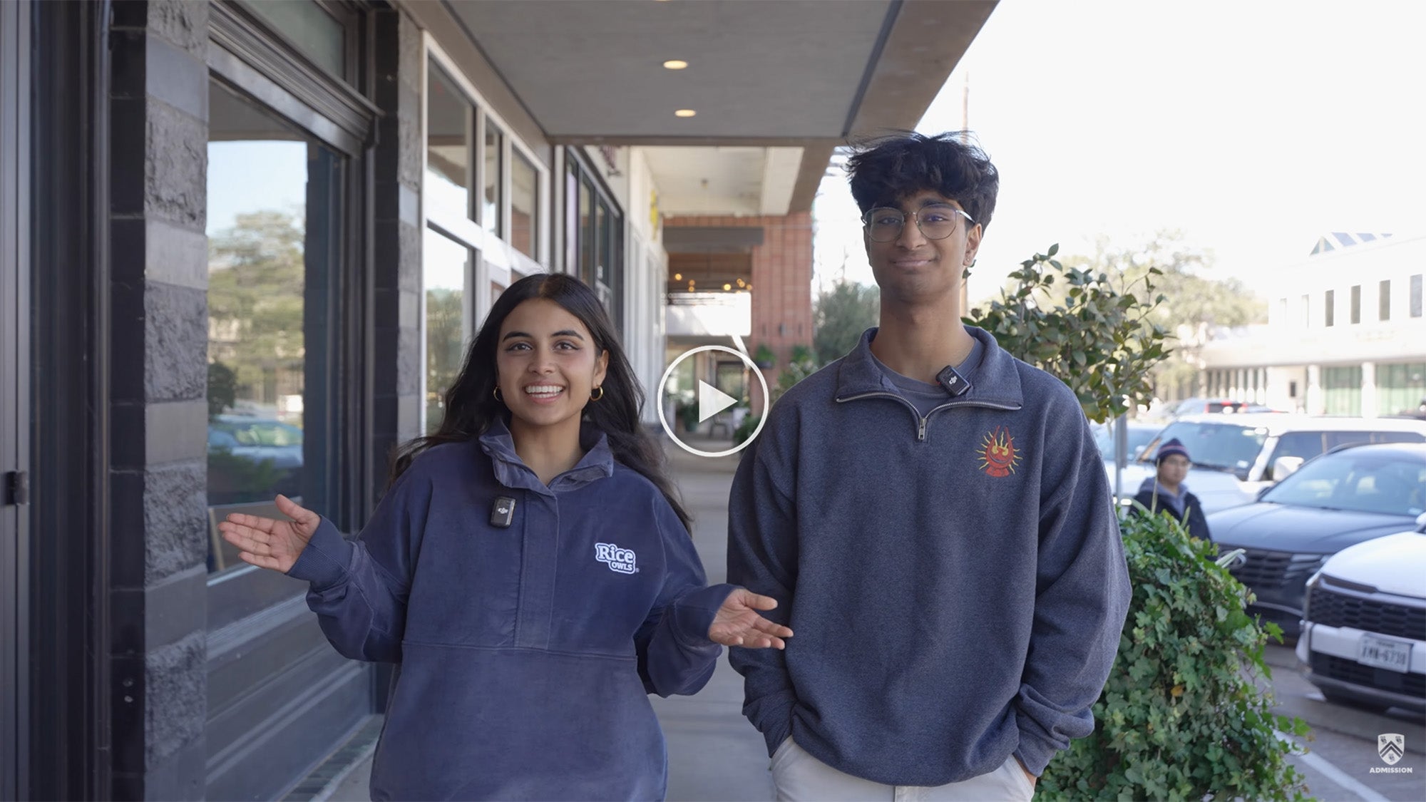 Two people looking at the camera, gesturing at the screen