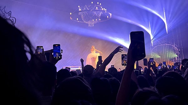 Phones up, recording a person standing on stage at a concert