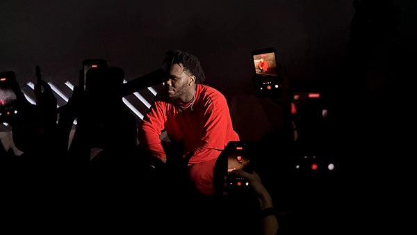 Darkly lit photo of phones recording a man crouching