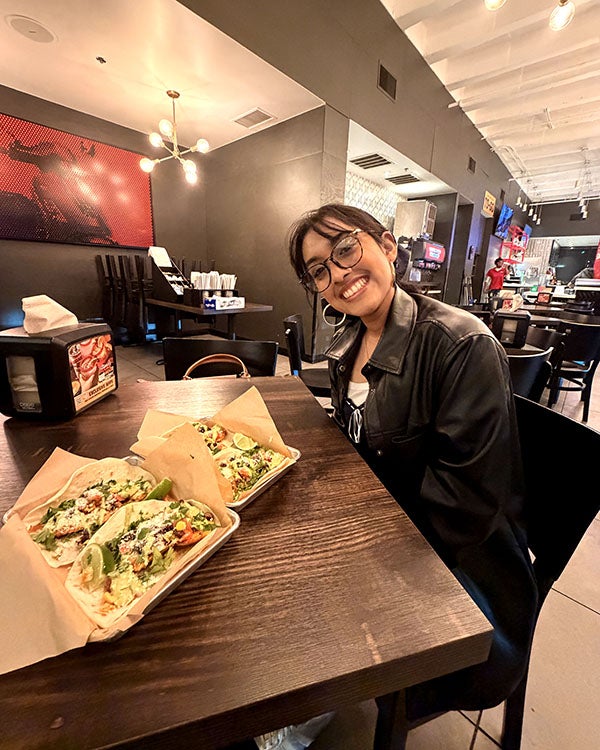 Girl smiling while sitting at a table with food in a restaurant