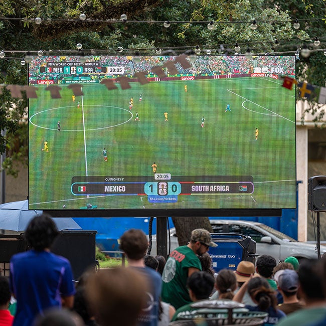 A large screen depicting a wide shot of a soccer field during a World Cup match.