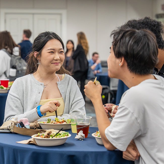 Two people speaking while eating from a burrito bowl