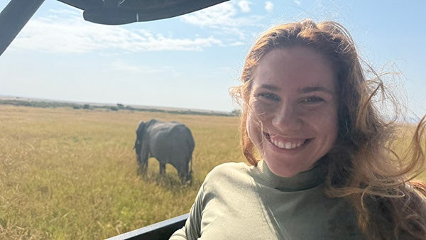 Close-up shot of a girl with a savannah and animal behind her