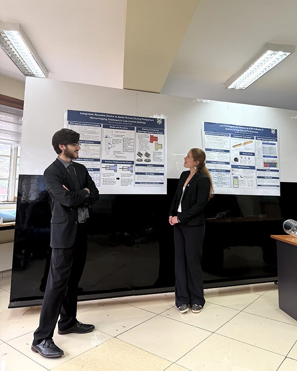 Two people standing in front of a research poster on a wall