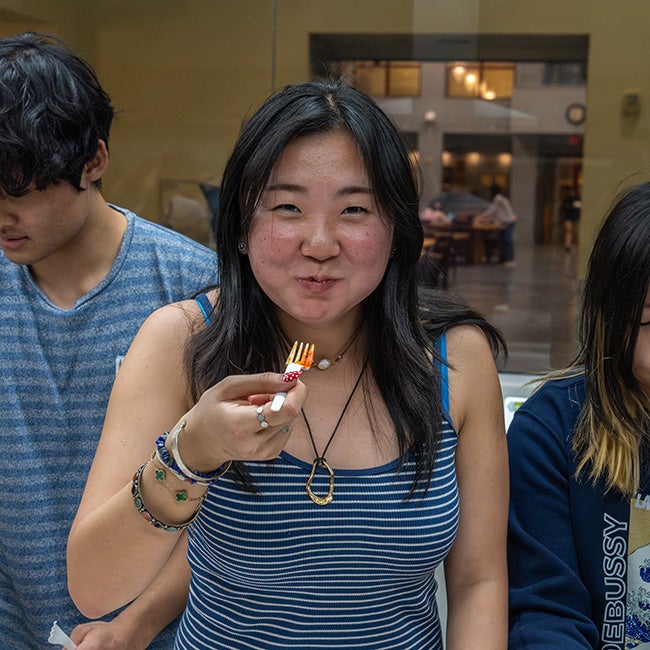 A girl mid-chew, holding a fork in front of her mouth