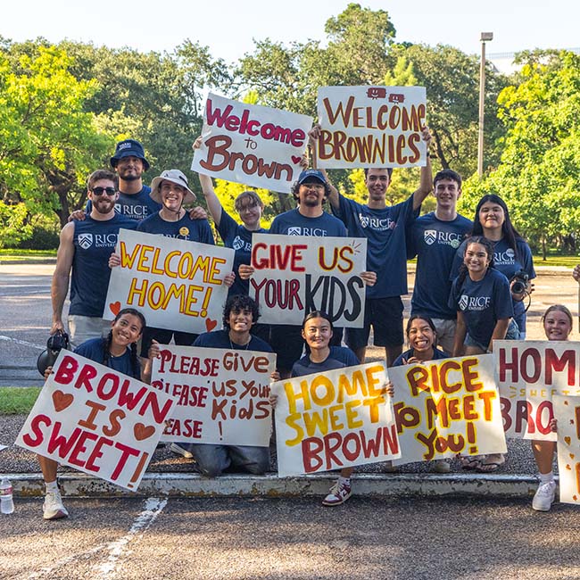 Group of people in matching blue shirts, holding up posters with large cheering messages